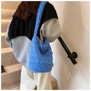 Détail du sac seau en fausse fourrure bleu électrique porté par un mannequin en escalier