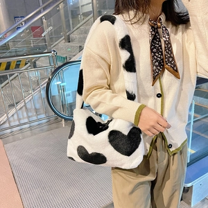 Détail d'un sac à bandoulière en peluche blanche avec des motifs de cœurs noirs