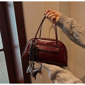 Detail view of glossy dark red PU leather bowling bag with cute puppy and chocolate charms
