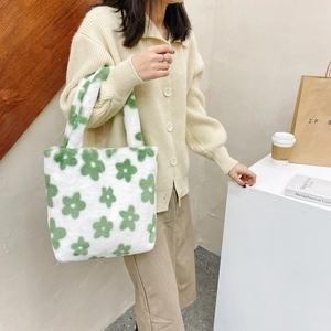 Detail showing the fluffy texture of a white plush tote bag with green floral pattern