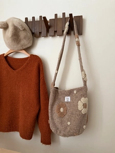 Close-up of brown plush shoulder bag with 3D floral accents and warm autumn knitwear