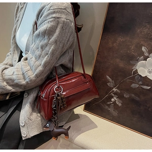 Detail view of burgundy PU leather shoulder bag featuring a cute dachshund dog charm