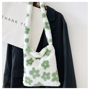 Détail d'un sac à bandoulière en peluche blanche avec motifs floraux verts sur un blazer