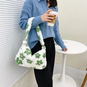 Detail of white faux fur shoulder bag with green floral patterns and fluffy strap