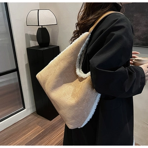 Détail du sac cabas en daim kaki avec bordure en laine blanche porté par un mannequin