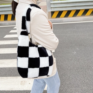 Vue de rue d'un sac fourre-tout en peluche à damier noir et blanc sur l'épaule d'un modèle