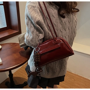 Close-up of wine red glossy PU leather shoulder bag with cute chocolate and dog charms