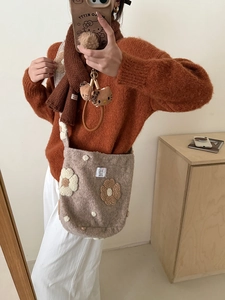 Close-up of brown plush shoulder bag featuring decorative 3D floral textures and soft fleece