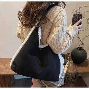 Détail d'un sac à bandoulière en daim noir avec bordure en laine d'agneau blanche douce