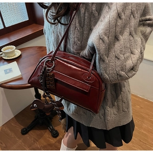 Detail of burgundy PU leather handbag with dachshund and chocolate charm accessories