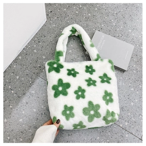 Détail d'un sac cabas en peluche blanche avec motif floral vert et anses solides