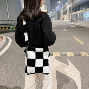 Street style view of a plush black and white checkerboard crossbody bag for autumn and winter