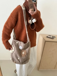 Detail of plush shoulder bag featuring 3D floral embroidery and a cute cat logo tag