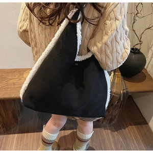 Dettaglio della borsa hobo in camoscio nero con bordo in pelliccia sintetica bianca e bottone