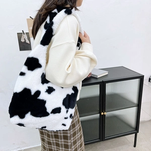 Detail of soft plush cow print tote bag with wide shoulder strap worn by a model