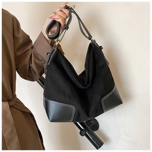 Detail of large black tote bag featuring matte suede contrast stitching and leather base