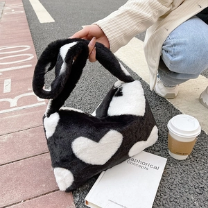 Détail du sac à main en peluche noir et blanc à motif cœur avec texture en fausse fourrure