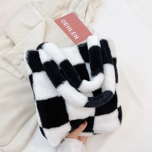Detailed top view of black and white checkered plush tote bag on knit sweater background