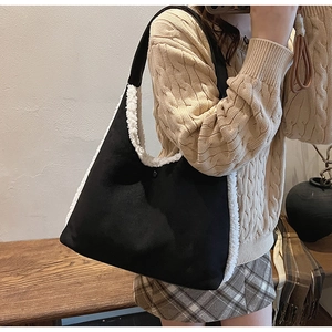 Dettaglio di una borsa tote in pelle scamosciata nera con bordo in peluche su una modella