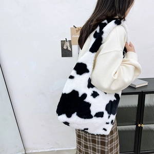 Detail view of the soft black and white cow print plush texture and wide shoulder strap