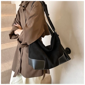 Detail view of black tote bag with white contrast stitching and matte texture finish