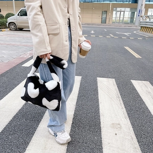 Vue de rue du sac cabas en fausse fourrure pelucheuse avec motif de cœurs noir et blanc