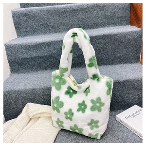 Détail de la texture douce du sac à bandoulière en peluche fleur verte sur tapis gris