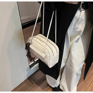 Detail of white PU leather crossbody bag featuring a decorative brown horse charm