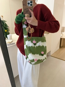 Detail view of plush green and white striped crossbody bag with pink floral accents