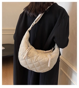 Detail of quilted nylon moon bag featuring double zippers and braided pulls on a crossbody style