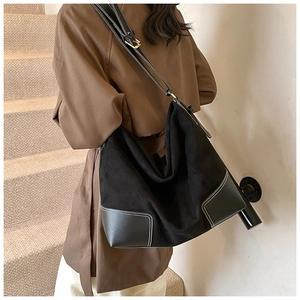Detail view of large black hobo shoulder bag with matte finish and white stitching contrast
