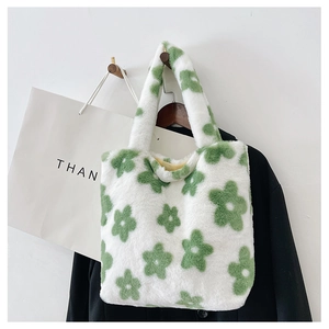 Détail d'un sac à main en peluche blanche avec motif floral vert suspendu à un crochet