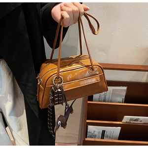 Detailed shot of retro brown PU leather handbag with animal charms and double zipper closure