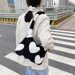 Photo de style urbain montrant le sac à bandoulière en peluche noir avec motif de cœur