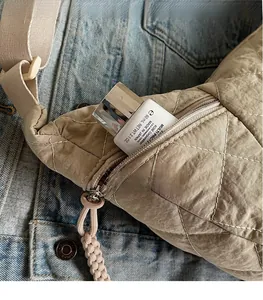 Macro view of the beige quilted nylon bag detail featuring a side zipper pocket and texture