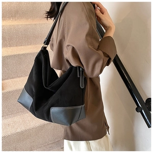 Detail of a large matte black tote bag with white contrast stitching and adjustable strap