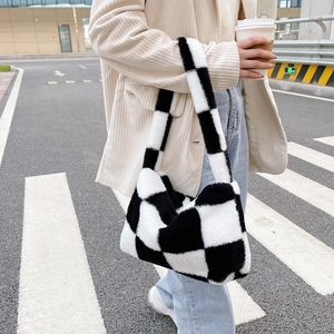 Chic black and white checkerboard plush handbag carried during an outdoor street walk