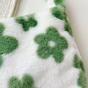 Close-up of soft plush fabric with green floral pattern and premium stitching detail