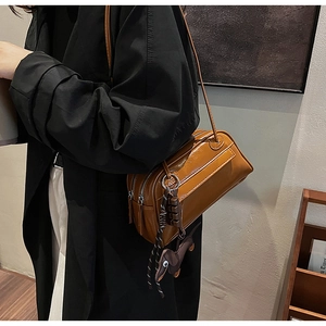 Detail view of retro brown crossbody bag with dachshund pendant on a model in black coat