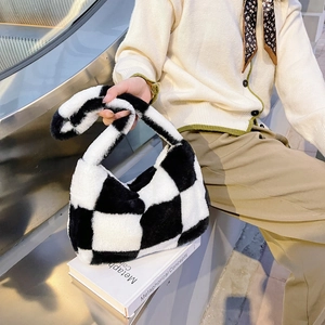 Detail of soft plush checkerboard handbag on a white book featuring faux fur texture