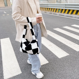 Street style view of a fluffy black and white checkerboard plush handbag for winter