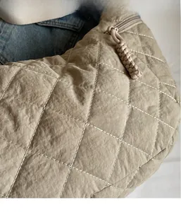 Detailed macro view of khaki quilted nylon fabric and woven knot zipper on the shoulder bag