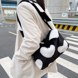 Détail du sac à bandoulière en peluche avec de grands motifs de cœur blanc et texture douce