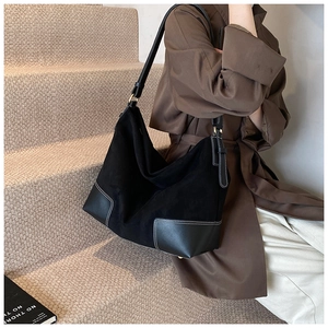 Detail of black large capacity hobo bag featuring matte texture and contrast white stitching
