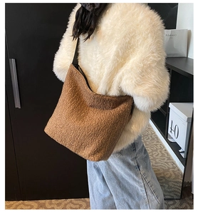 Brown fluffy faux shearling bucket bag with wide black strap shown on model shoulder