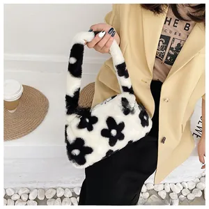 Detail of soft black and white plush floral tote bag held by a model in a city setting