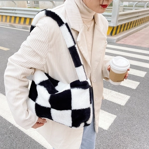 Close-up of black and white checkerboard plush shoulder bag on street background