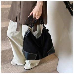 Detail view of large black suede hobo bag with contrast stitching and leather panels