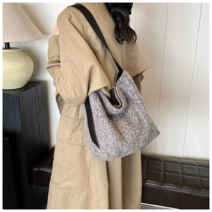 Detail of grey tweed tote bag with black leather strap worn with an autumn trench coat