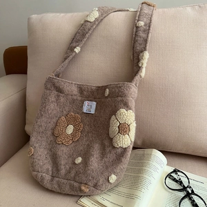 Chic autumn brown plush shoulder bag with 3D floral pom-pom decor on a sofa